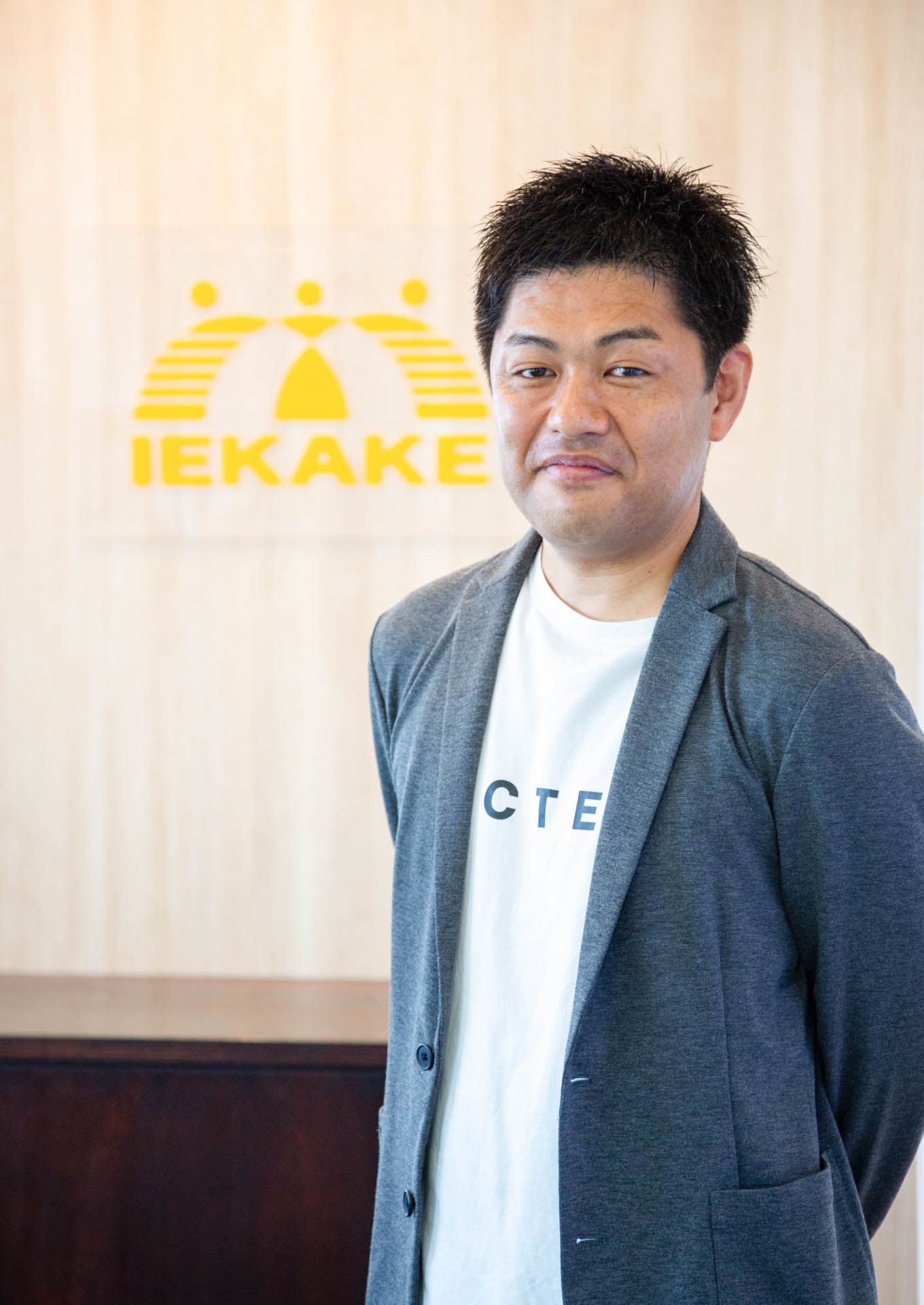 IEKAKEのロゴの前に立つ代表 福本 徹
