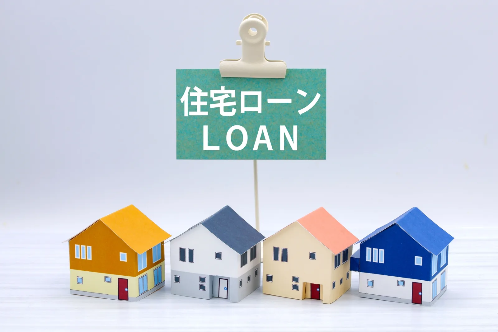 「住宅ローン LOAN」と書かれた立て札と、色違いの家の模型