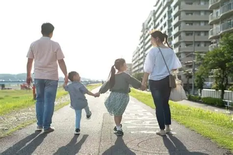 手をつないで歩く4人家族の後ろ姿