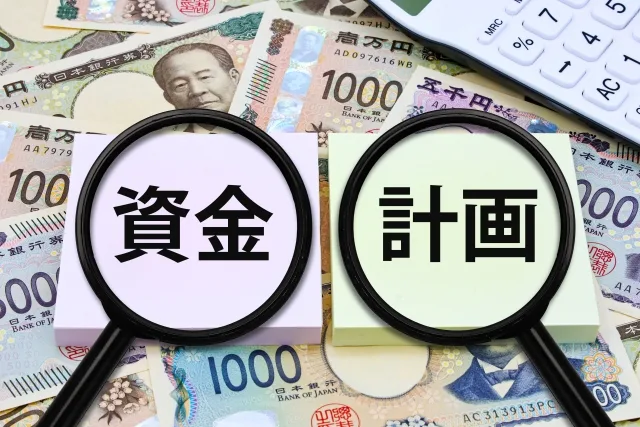 「資金計画」の文字を虫眼鏡で拡大したイメージと紙幣